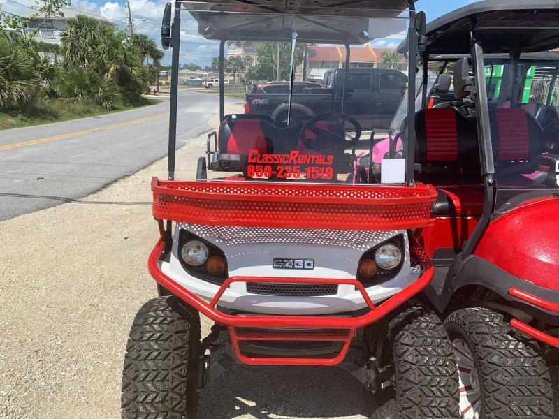 Red and white lifted golf cart with a red brush guard